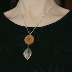 Halsband med drivved av björk och ett löv i metall