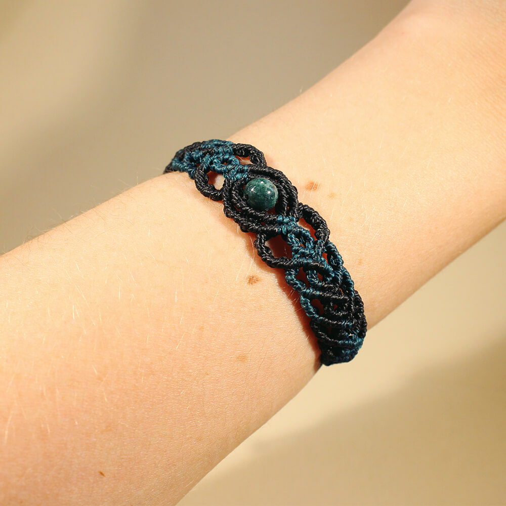 Ett svart och blått armband i makramé med en turkos pärla av agat