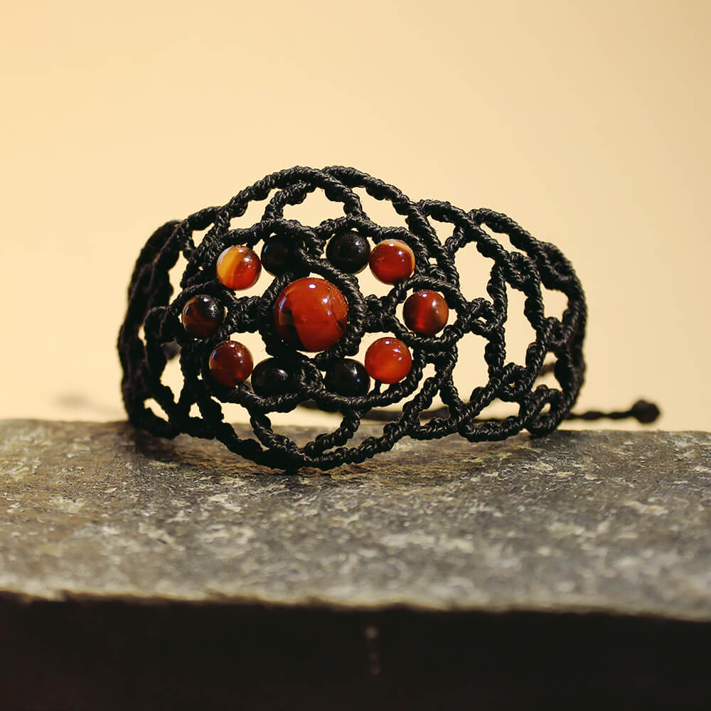 Svart armband med drömagat, knutet i makramé, med 15 stenpärlor.