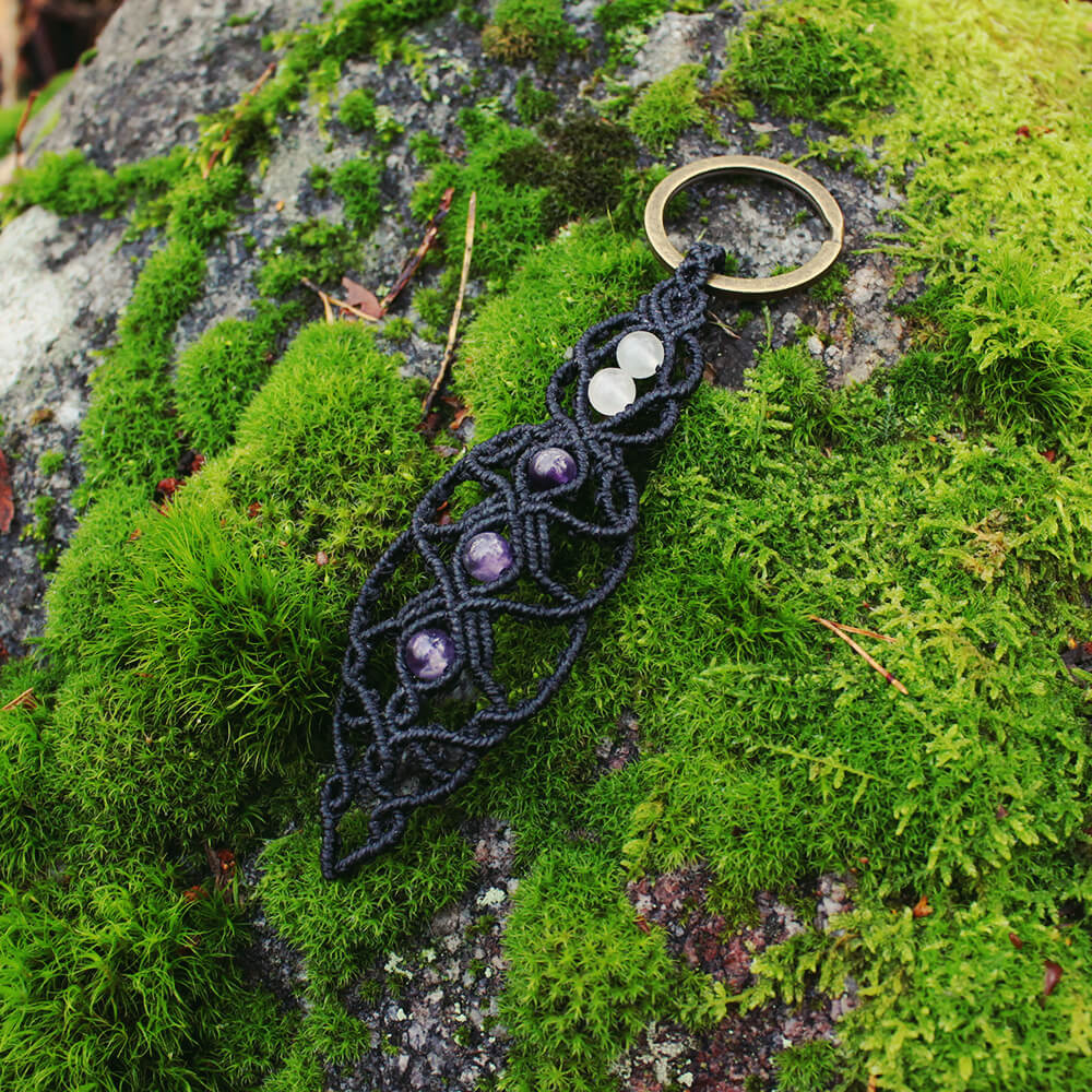 En svart nyckelring i makramé med pärlor av bergkristall och ametist