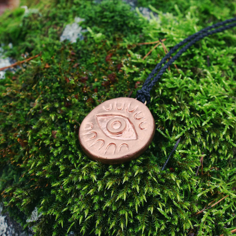 Ett halsband med ett &ouml;ga som ligger p&aring; mossa