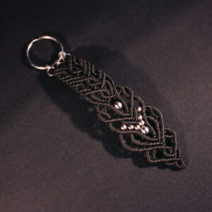 Svart nyckelring i makramé med pärlor av rostfritt stål.